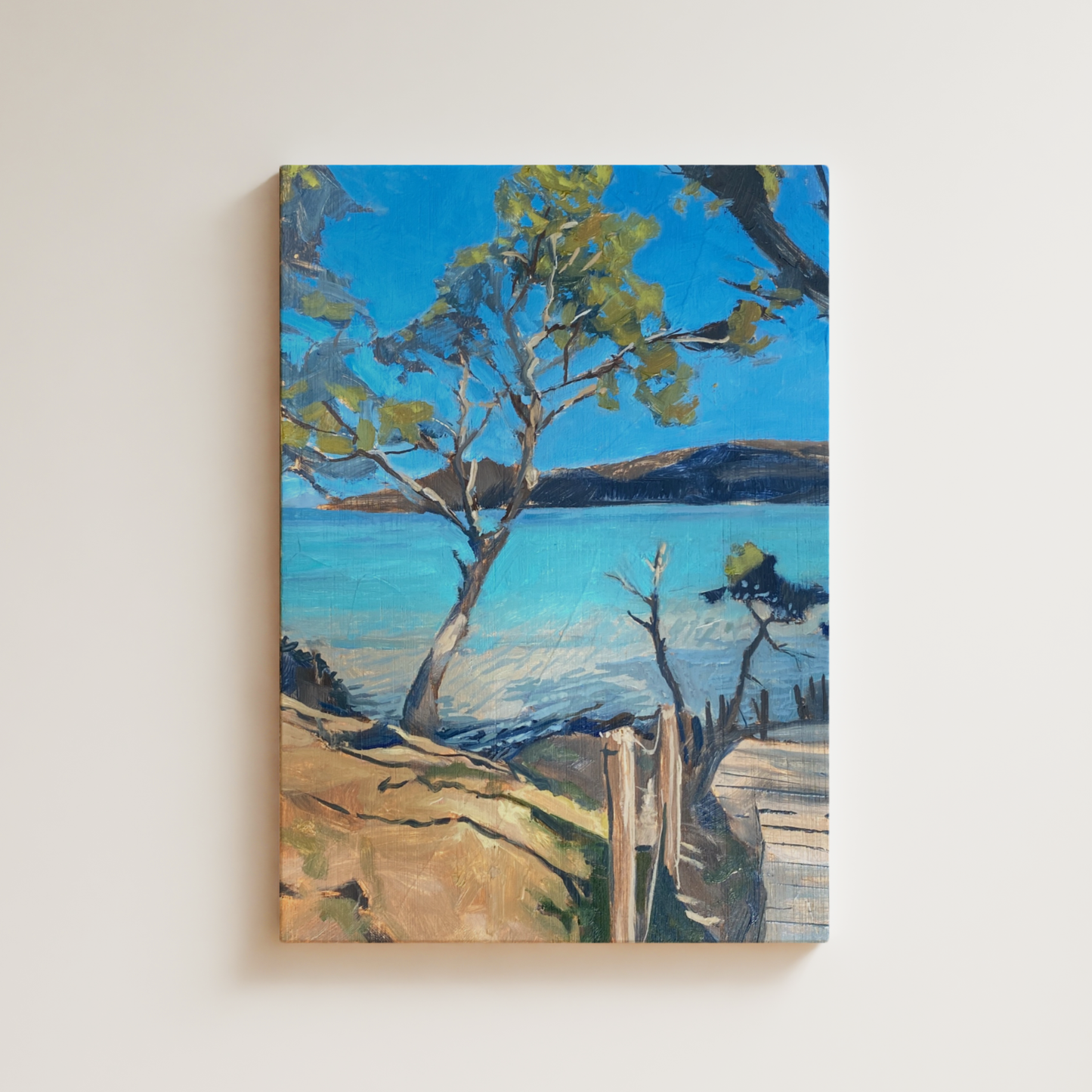 Painting of a landscape with a tree and body of water on a white wall.
